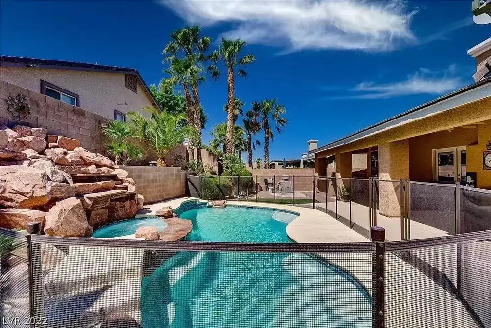 Pool, rock spa, and palm-lined patio