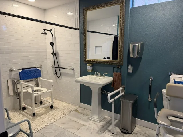 A walk-in shower with a bench and grab bars for safety