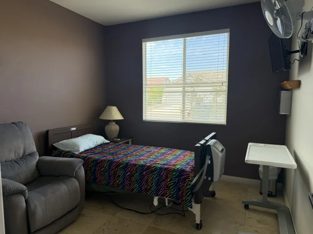 A bright private resident room with a recliner and window view